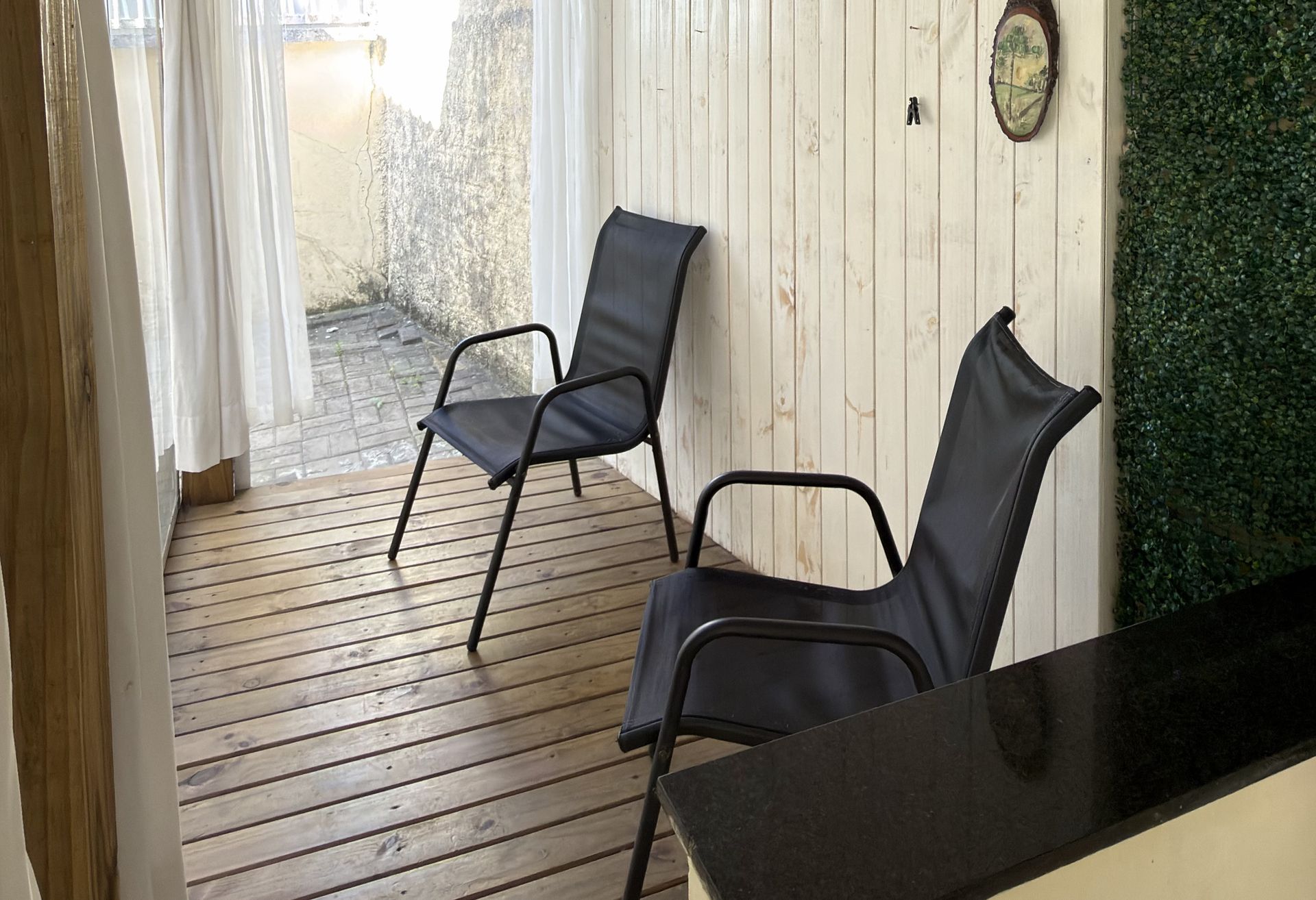 A varanda do Quarto 2, com deck de madeira, duas cadeiras e a bancada.