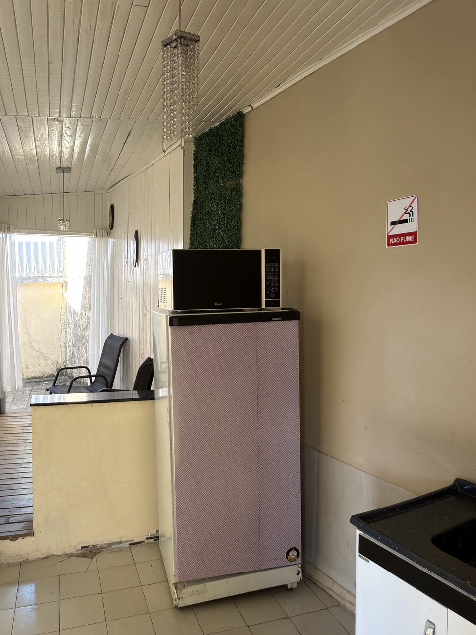 A cozinha do Quarto 2: pia, frigobar e micro-ondas, com a varanda ao fundo.