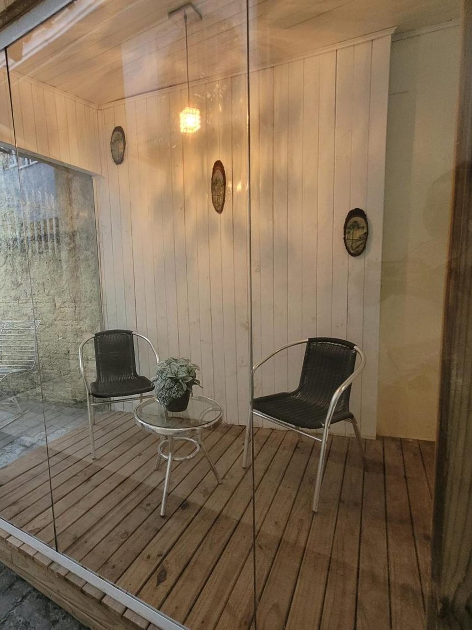 A varanda envidraçada do Quarto 2, com o deck de madeira e as cadeiras.