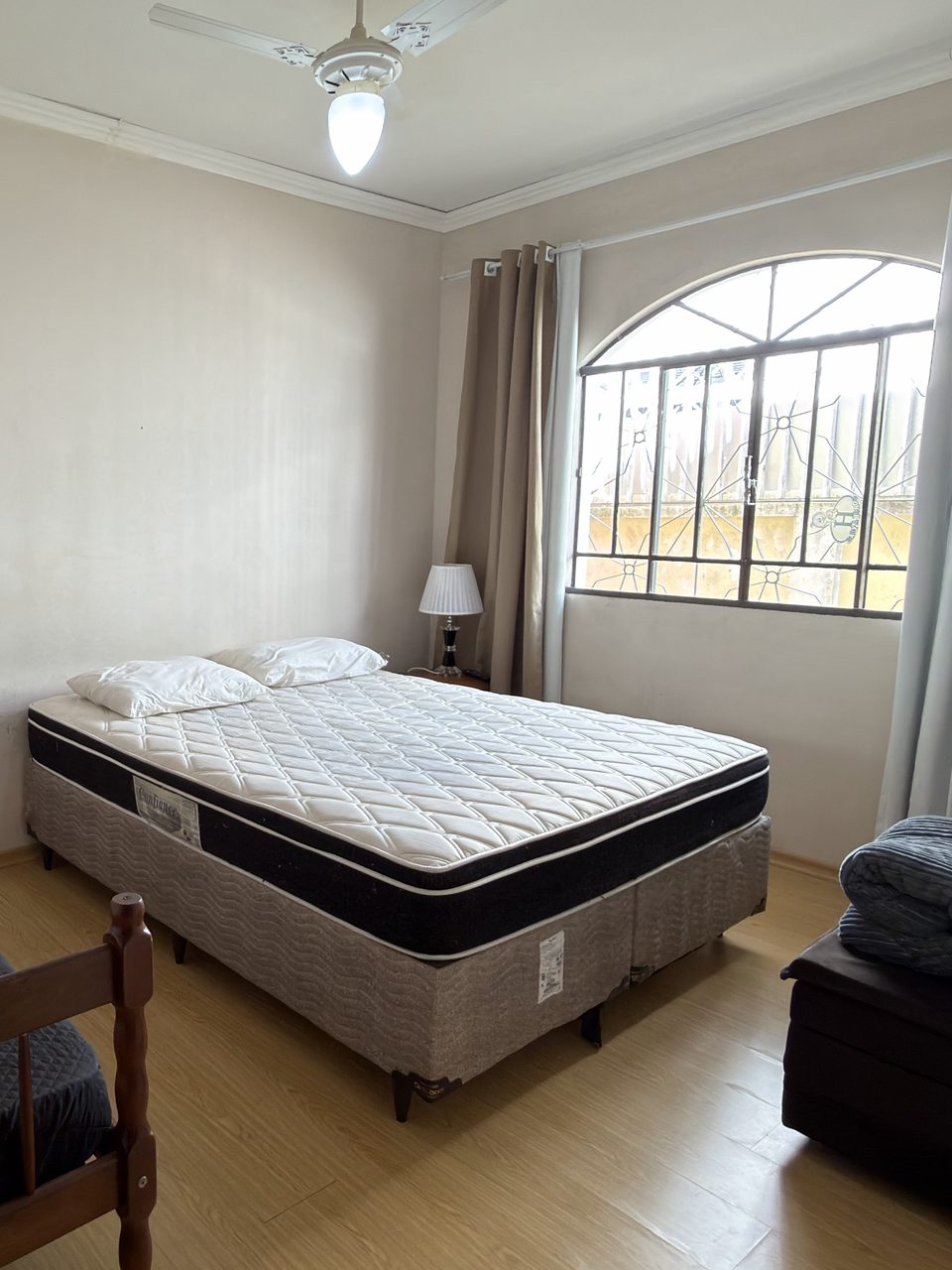 O Quarto 4: a cama de casal e a janela em arco, com piso de madeira.